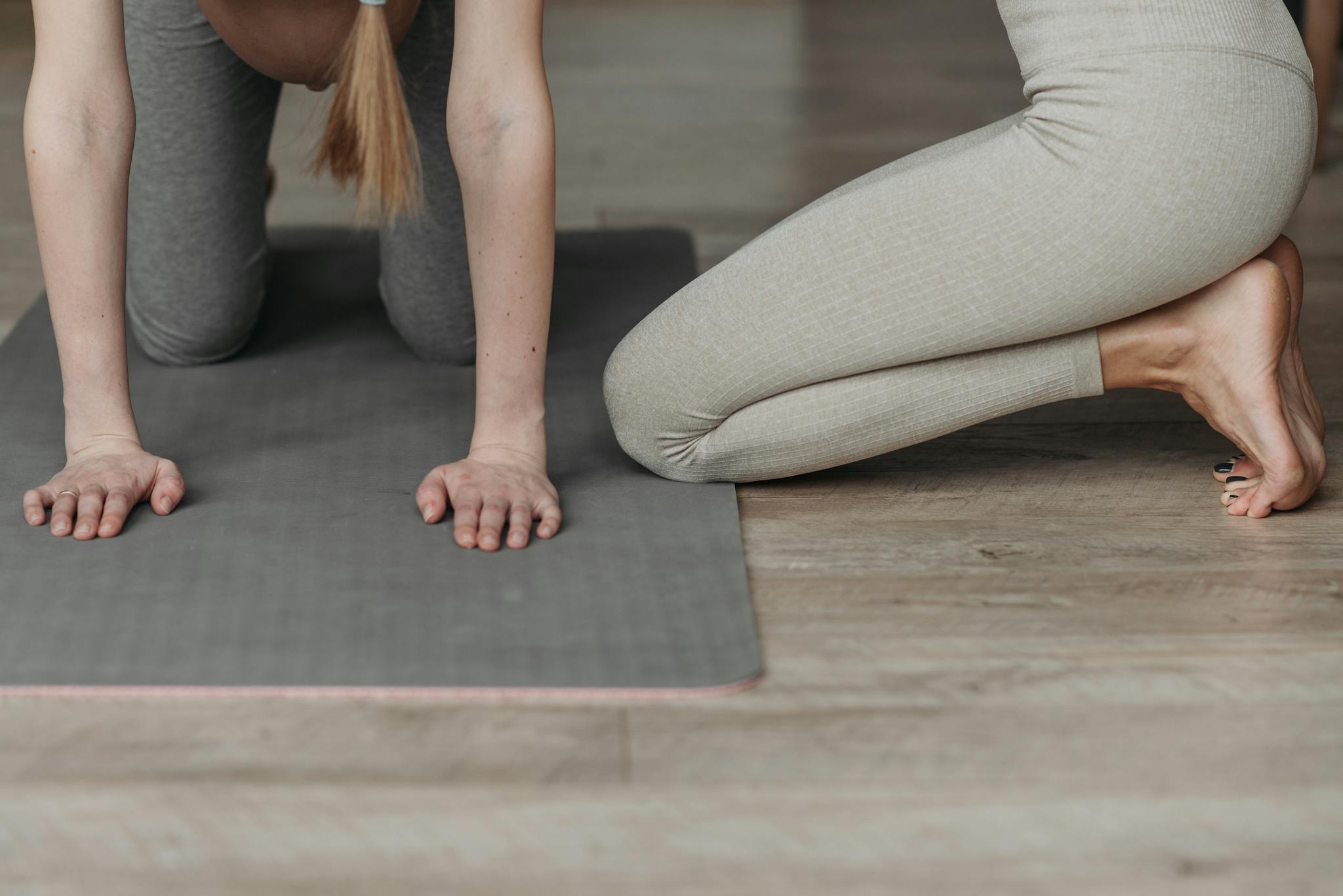 Pregnant woman on yoga mat engaging in prenatal exercise routine indoors.
